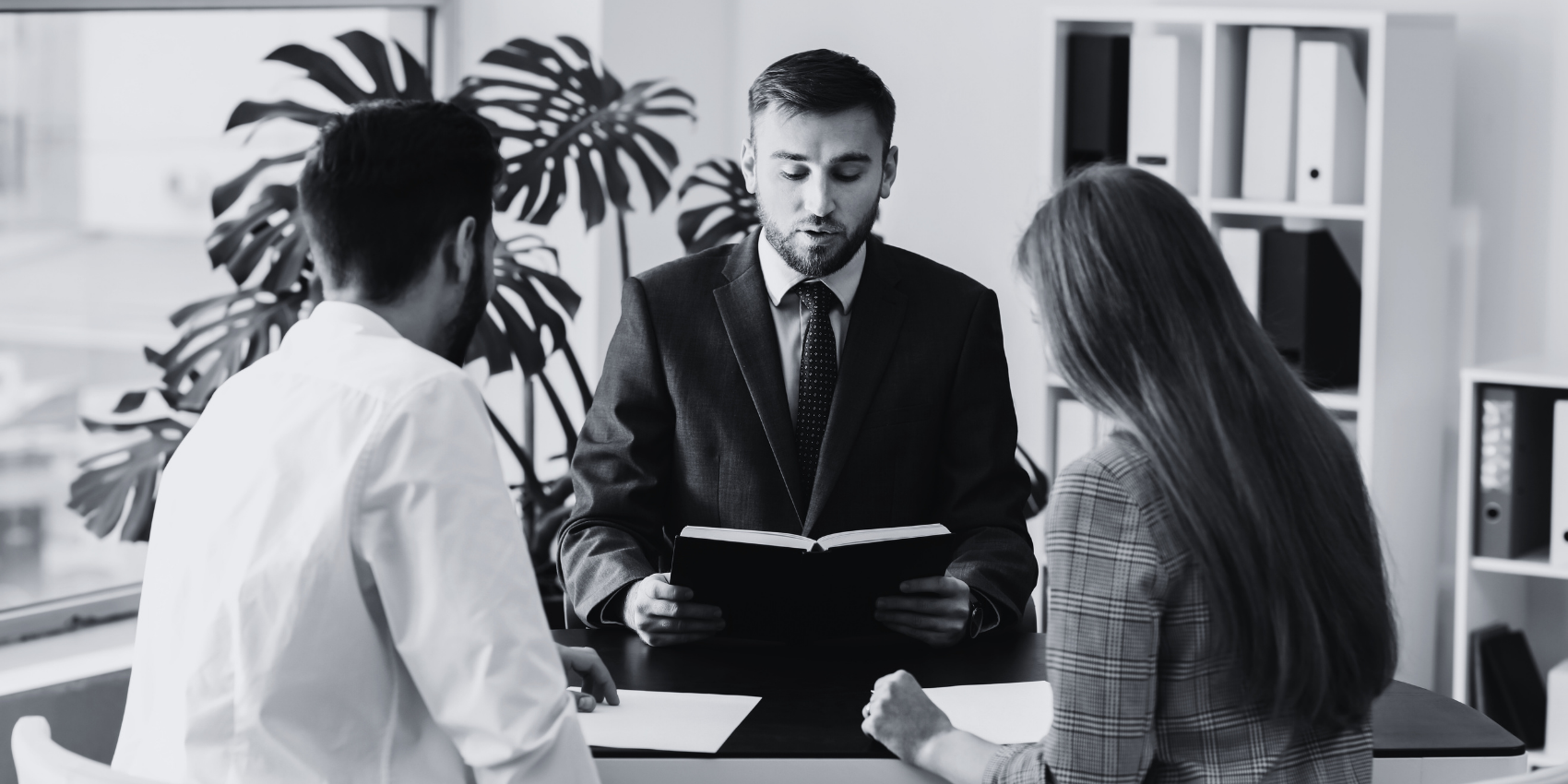 A lawyer speaking to a couple while looking into his journal.