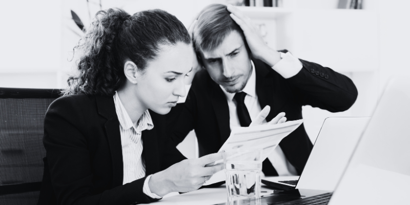 A man and a woman going through a document and looking frustrated