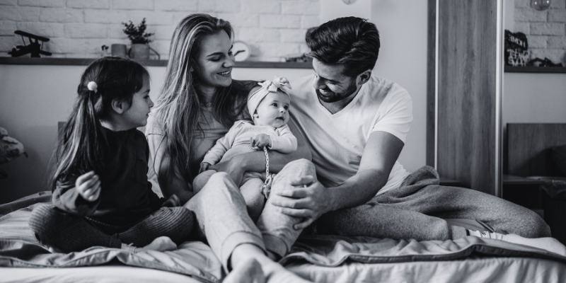 A happy family with the dad and mom together with two kids.
